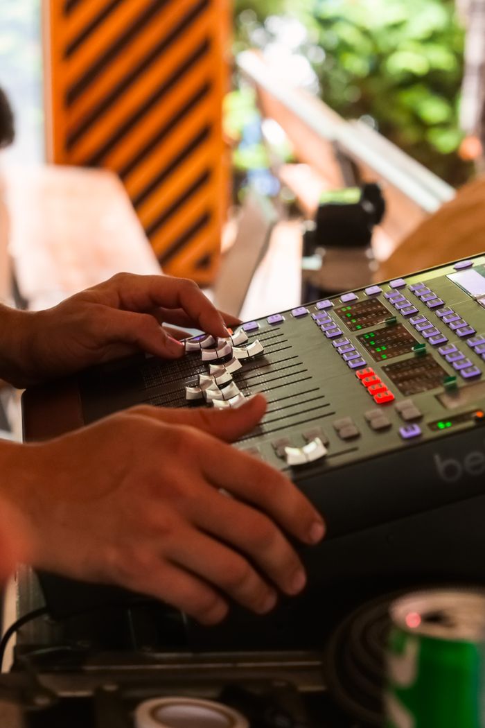 Close-up of hands adjusting controls on an audio mixer, creating music indoors.