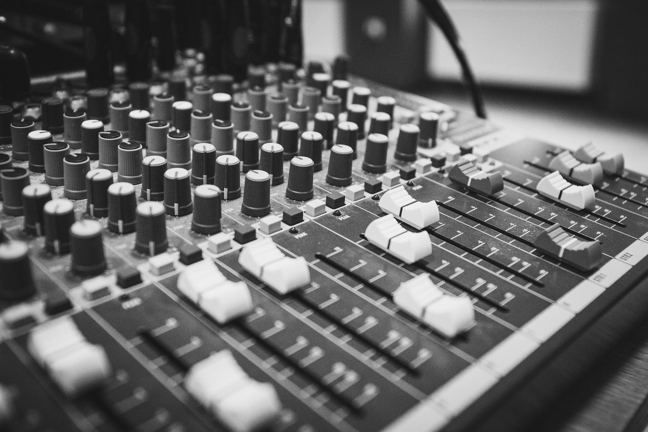 About Detailed view of an audio mixing console with knobs and sliders, captured in black and white.