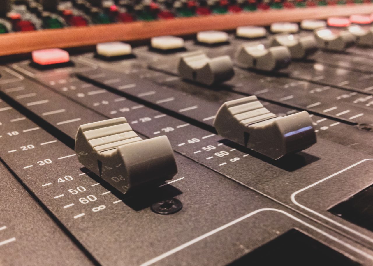 Detailed view of audio mixer console with control faders in a studio setting.